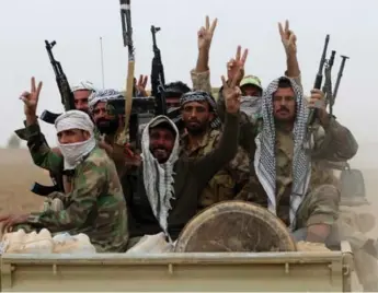  ?? AHMAD AL-RUBAYE/AFP/GETTY IMAGES ?? Shiite fighters flash the sign for victory as they enter the village of Abu Shuwayhah, south of Mosul, on Tuesday.