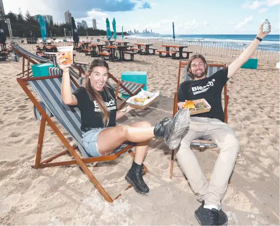  ?? Picture: JASON O’BRIEN ?? Kersten Marchant and Jed Murray enjoy the offerings at the Burleigh Bleach* Club bar on the sand in front of Justin’s Park.