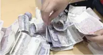  ?? — Reuters ?? A shop assistant counts piles of British Pound Sterling banknotes at an Apple store in London.