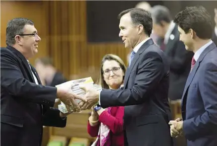  ?? Sean KilpatricK / tHe canaDian preSS ?? Prime Minister Justin Trudeau looks on as Finance Minister Bill Morneau tables the federal budget documents in the House of Commons.