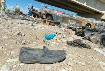  ?? ISMAIL SASOLI/GETTY-AFP ?? Debris and passenger belongings are scattered across the ground after a bus crashed into a pillar and fell off a bridge, catching fire and killing 40 people Sunday near the town of Bela in southern Pakistan, officials said. The bus was carrying 44 travelers from Quetta in Balochista­n province to Karachi in Sindh province. Four injured passengers were rescued.