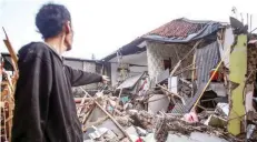  ?? — Reuters ?? A local stands near houses damaged after earthquake hit in Cianjur, West Java province, Indonesia, on Monday.