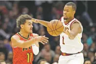  ?? TONY DEJAK/ASSOCIATED PRESS ?? The Hawks’ Trae Young, left, passes against the Cavaliers’ Rodney Hood during Tuesday’s game in Cleveland. Young scored 24 and Hood scored a season-high 26 in the Cavaliers’ first win since firing coach Tyronn Lue.