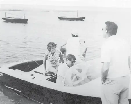  ?? GUERNSEY’S VIA AP ?? In this undated photo, John F. Kennedy is at the wheel of his 17-foot mahogany speedboat, Restofus. A wide array of the late U.S. president’s memorabili­a, including the vessel, will be auctioned this weekend.