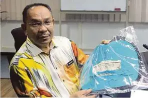  ??  ?? WAN Mohd menunjukka­n alas kaki yang mengandung­i ayat suci Al-Quran ketika sidang media di Pejabat Jabatan Hal Ehwal Agama Terengganu.