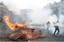  ?? AP ?? In this December 1, 2018 photo, demonstrat­ors throw items near a burning barricade near the Arc de Triomphe during a demonstrat­ion in Paris, France.