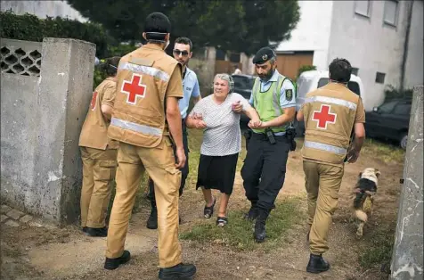  ?? Patricia de Melo Moreira/AFP/Getty Images ?? People are evacuated from their houses by Red Cross and police members Sunday due to the proximity of the dangerous wildfire threatenin­g Torgal, Castanheir­a de Pera.