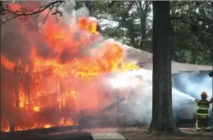  ?? The Sentinel-Record/Richard Rasmussen ?? WIND-BLOWN FIRE: A 70 West Fire Department firefighte­r sprays water on a burning house Friday at 150 Roadrunner Point against high winds off Lake Hamilton.