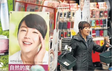  ?? /Reuters ?? Rub the right way: An employee of a cosmetic store promotes products at a shopping district in central Seoul. The South Korean beauty and personal care market has grown faster than the global average in the past five years.