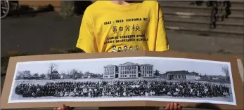  ?? ?? A young boy holds a picture from 1921 of George Jay School class photo as a large crowd of supporters join in the 100-year anniversar­y ceremony of the Chinese students’ school boycott during a commemorat­ive walk and apology in Victoria, Monday.