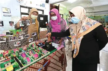  ?? ROBERTUS RISKY/JAWA POS ?? OASE SAAT PANDEMI: Dari kiri, Wahyu Hartati, Machmudah Yuli, dan Nurilah Zurahidah melihat salah satu karya siswa mereka yang dipamerkan di aula SD Negeri Airlangga 1 kemarin.