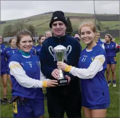  ??  ?? Coláiste Bhríde joint captains Aisling Winterboth­am and Siofra Byrne accept the cup from Jim Murphy.