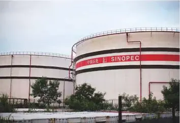  ?? Bloomberg ?? Sinopec Ltd. storage tanks in a tank farm in Hong Kong. The globe’s largest oil refiner will process less oil on the back of weaker demand and competitio­n from privately owned rivals.