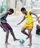  ??  ?? As the rain poured, these boys were seen enjoying a game of football along Wildman Street.