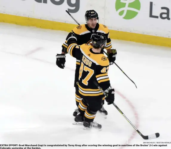  ?? JIM MICHAUD / BOSTON HERALD ?? EXTRA EFFORT: Brad Marchand (top) is congratula­ted by Torey Krug after scoring the winning goal in overtime of the Bruins’ 2-1 win against Colorado yesterday at the Garden.