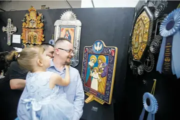  ??  ?? Nicolas Madrid and his daughter, Mila, 5, check out a winning collaborat­ion piece he did with best of show winner Nicolás Otero on Friday during the Traditiona­l Spanish Market preview at El Museo Cultural.