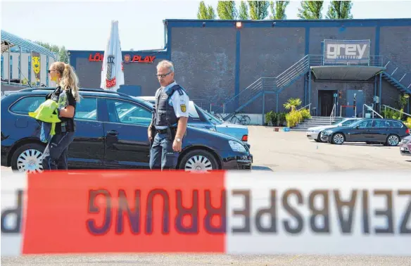  ?? FOTO: AFP ?? Am Morgen nach der Tat sichern Polizisten Spuren und sperren den Tatort ab. 100 Ermittler sind im Einsatz, um die Hintergrün­de der Schießerei zu klären.