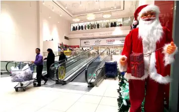  ?? — Reuters photo ?? People walk out of Mega Mart supermarke­t as Santa Claus figure is displayed at the entrance in Manama, Bahrain.