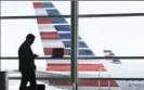  ??  ?? A passenger talks on the phone as American Airlines jets sit parked at gates at Washington's Ronald Reagan National Airport.