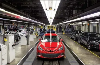  ?? Bloomberg News/BARTEK SADOWSKI ?? Workers inspect Opel Astra vehicles during quality control checks at the end of the production line at the Opel automobile plant in Gliwice, Poland, on Monday. The maker of Peugeot and Citroen cars will pay $2.2 billion for GM’s Opel unit and its U.K....