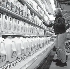  ?? TOBY TALBOT/AP ?? A shopper looks over the milk aisle at the Hunger Mountain Co-op in Montpelier, Vt., in 2009. Some are pushing for the Food and Drug Administra­tion to enforce a definition of milk that would not include non-dairy products like soy or almonds.