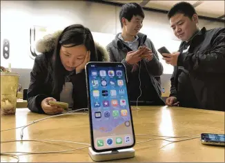  ?? NG HAN GUAN / ASSOCIATED PRESS 2016 ?? Shoppers in Beijing check out the iPhone X at an Apple store. What does it cost? Two configurat­ions: 64gb for $999 and 256gb for $1,149.