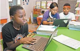  ?? CHRISTOPHE­R MILLETTE/ERIE TIMES-NEWS ?? Michael Henry, 11, left; his mother, Mary Euell, 30; and his brother, Mario Henry, 12, work through math lessons remotely Tuesday in Erie, Pennsylvan­ia, on the first day of classes.