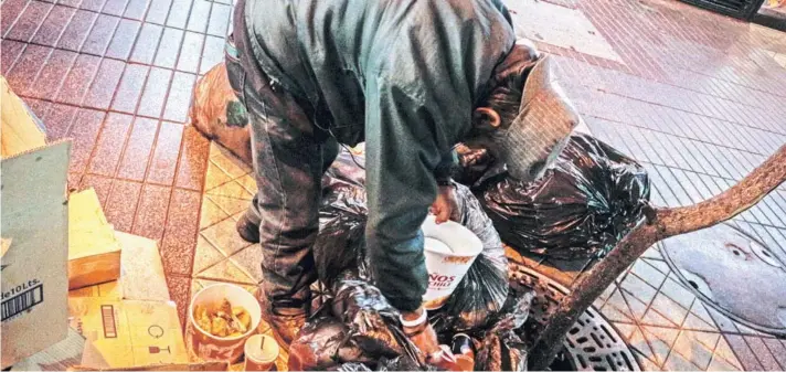  ??  ?? ► Humberto “Michael” busca entre los restos afuera de un local de comida rápida en el centro de Santiago.