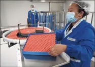  ?? Associated Press ?? A worker feeds vials for production of SARS CoV-2 Vaccine for COVID-19 at the SinoVac vaccine factory in Beijing last month. China said on Friday that it is joining the COVID-19 vaccine alliance known as COVAX.