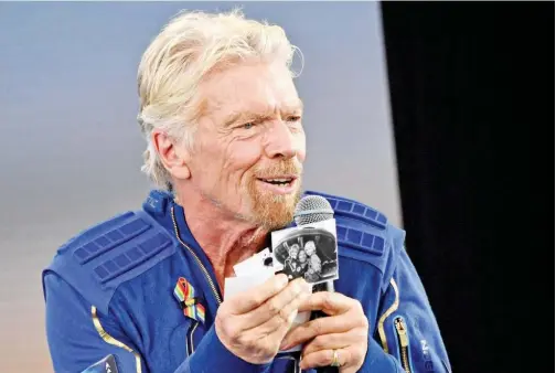  ?? Agence France-presse ?? Sir Richard Branson holds up photos that he brought with him into space, as he speaks after flying into space aboard a Virgin Galactic at Spaceport America, New Mexico, on July 11, 2021.