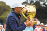  ?? Simon Baker / AFP via Getty Images ?? USA captain Tiger Woods holds the Presidents Cup after their win on Sunday.