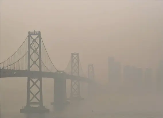  ?? Nick Otto / Special to The Chronicle ?? The Bay Bridge and San Francisco skyline, seen from Treasure Island, are barely visible through Sept. 11’s hazy air because of smoke from the state’s wildfires.