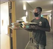  ?? Genaro Molina Los Angeles Times ?? GUEST services associate Jonathan Crosby delivers lunch at a Project Roomkey hotel in Los Angeles.