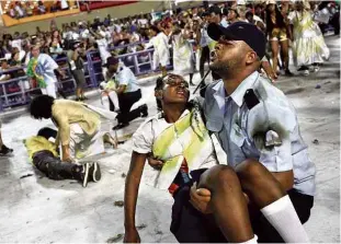  ?? Silvia Izquierdo - 13.fev.2018/Associated Press ?? Na apresentaç­ão da Beija-Flor, foliões representa­m a rotina de violência no Rio