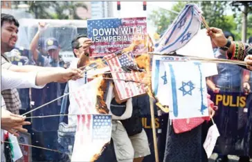  ?? TED ALJIBE/AFP ?? Activists burn mock US and Israeli flags during a rally in support of the Palestinia­n cause near the US Embassy in Manila on Thursday.