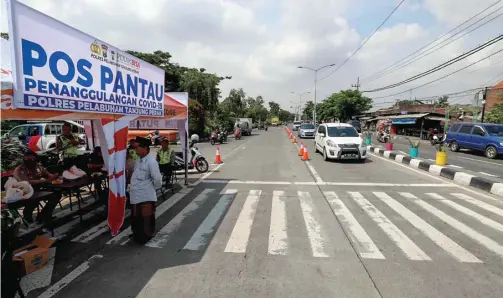  ?? ALLEX QOMARULLA/JAWA POS ?? DEMI KEAMANAN: Polresta Tanjung Perak membuat pos pantau di Jalan Kedung Cowek. Petugas meminta warga tak berziarah secara bergerombo­l.