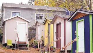  ?? ELAINE THOMPSON/ASSOCIATED PRESS ?? A row of tiny houses at a Seattle homeless encampment stands in full view of a full-size home behind it on Nov. 9.