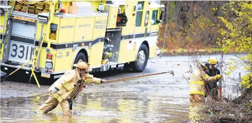  ?? PHOTOS BYRICKKINT­ZEL/THE MORNING CALL ?? Nick Marlowe, of the Han-Le-Co Fire Company, stretches to clear more debris Monday as members of his company and Catasauqua work to open Weaversvil­le Road in Hanover Township. According to Marlowe, a vehicle was trapped in the water and then was pushed out.