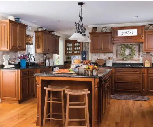  ??  ?? Above: The modern, open kitchen gets the cozy treatment with a blend of vintage and thrifted pieces. Old crocks corral utensils, a magnolia leaf wreath and a sign decorate the stove area, and groups of vintage scales line the tops of the cabinets.