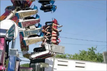  ?? JONATHAN TRESSLER — THE NEWS-HERALD ?? Fair-goers smile sideways while riding a topsy-turvy ride in the parking lot of Kirtland High School June 14 during the first hours of the 59th annual Kirtland Kiwanis Strawberry Festival.