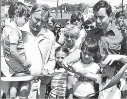  ?? BALTIMORE SUN
RALPH ROBINSON/ ?? Robert A. Pascal, left, holds Bradley Falk while former Annapolis Mayor John Apostol, right, cuts a ribbon to open the 16th annual Annapolis Arts Festival in June 1978.