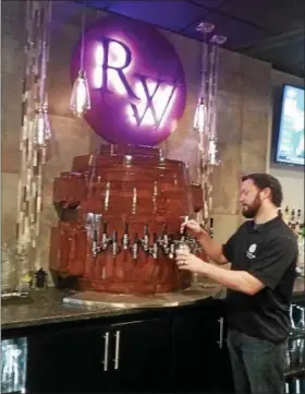  ?? JEAN BONCHAK — FOR THE NEWS-HERALD ?? Nick Ovsenik, co-owner of Ridgewood Kitchen & Spirits in Concord Township, pours a libation from the beer tower, an industrial piece of equipment that was renovated and repurposed after being purchased from an old foundry.