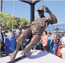  ?? JAE C. HONG/ASSOCIATED PRESS ?? Fans look at the bronze statue depicting former Dodger great Jackie Robinson, which made its debut on Saturday at Dodger Stadium.