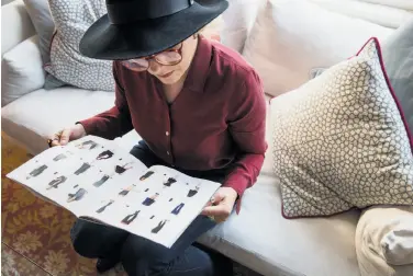  ??  ?? Kassie Borreson, a guest at an in-home demonstrat­ion, looks through a catalog of Ruby Ribbon garments during the direct sales party in Noe Valley. Ruby Ribbon uses retro marketing in the age of Amazon.