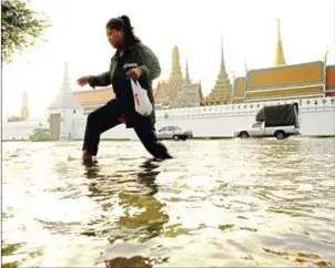  ?? AFP ?? A woman walks through floodwater­s in front of the Grand Palace near the Chao Praya river in Bangkok on October 28, 2011.