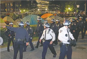  ?? JULIA WU/AFP VIA GETTY IMAGES ?? New York police officers in riot gear enter Columbia University's encampment as they enter a building that had been barricaded by pro-palestinia­n student protesters in New York City on April 30.