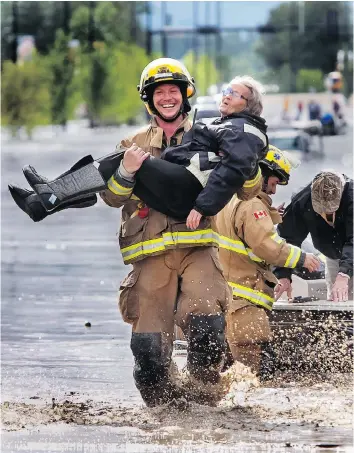  ?? LYLE ASPINALL/FILES ?? A firefighte­r carries a woman out of a flood zone in High River, Alta. on June 20, 2013. Extreme flooding from the Highwood River prompted a townwide evacuation.