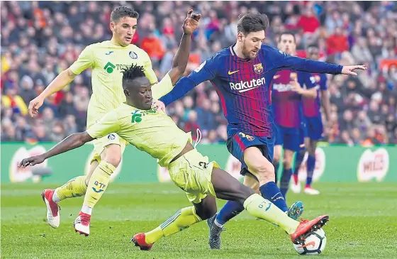  ??  ?? Barcelona’s Lionel Messi, right, vies with Getafe’s Dakonam Djene during a Spanish league match last week.