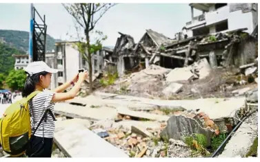  ?? — AFP ?? Disaster site: A girl taking pictures of houses damaged during the 2008 earthquake in Beichuan, Sichuan province.