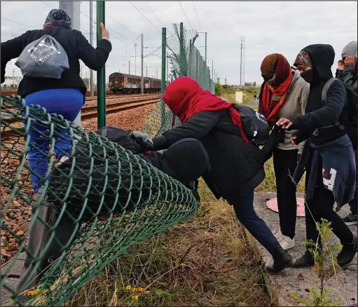  ??  ?? Breach: Migrants break through a fence near train tracks as they attempt to access the Channel Tunnel near Calais yesterday